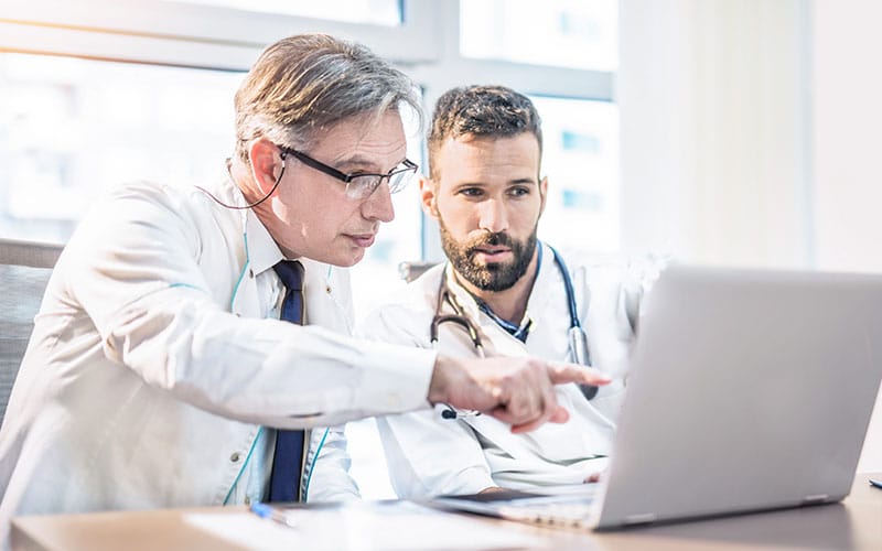 Two physicians review a case together on the computer