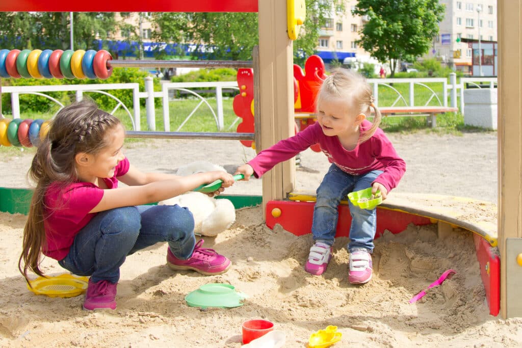 kids fighting in a sandbox at the playground