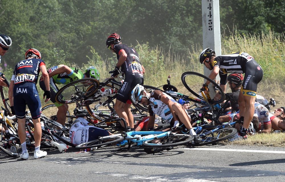 Cyclists in the 2015 Tour de France are in a jumble of people and bikes at the side of the road