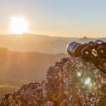 binoculars on top of rock mountain at beautiful sunset background.